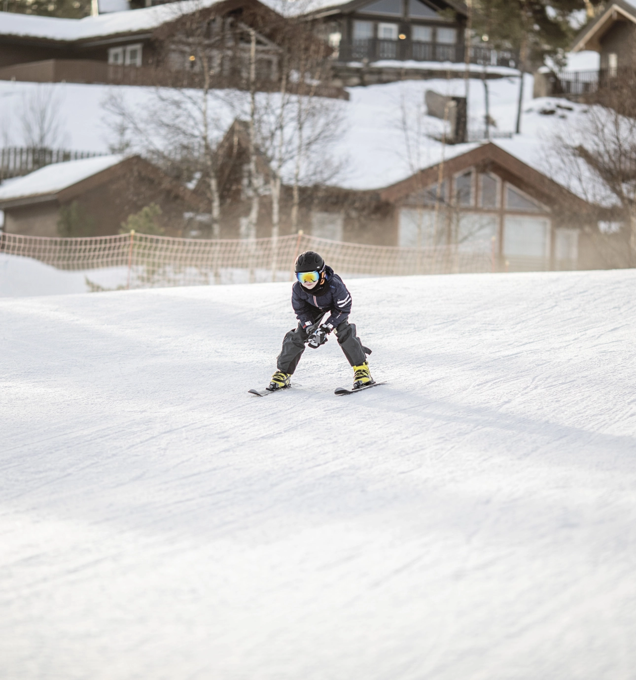 Dreng står på ski foran hytterne i Vrådal